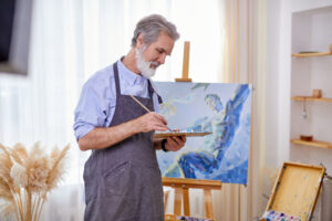 senior artist painting on easel, canvas, intelligent professional painter enjoys art