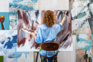 Woman artist is drawing on canvas with brush