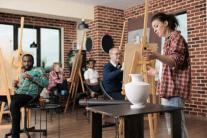 Group of diverse people learn how to draw realistic items, listening teacher and drawing on canvas. Family involved in art activity spending time together. Creative leisure activities for adults