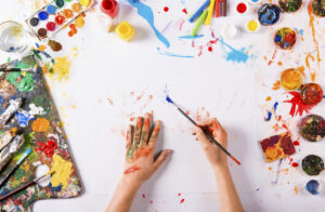 painter painting on canvas with paintbrush from above