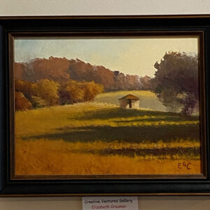 “In the Twilight of the Season” by Elizabeth Craumer shows a small shed in a sunny field with trees and shadows behind.