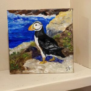 Puffed Up" by Susan Beers is a small painting of a puffin on a rocky shore with blue water and greenery behind.